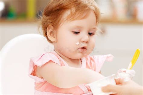 A Baby Eating Yogurt With Some On Her Face Stock Image Image Of Home