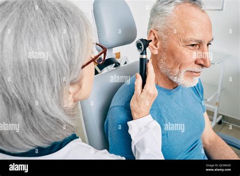 Otolaryngologist Doctor Checking Senior Mans Ear Using Otoscope Or