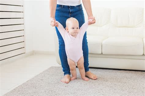 Bebé Dando Los Primeros Pasos Con La Ayuda De La Madre En Casa Foto