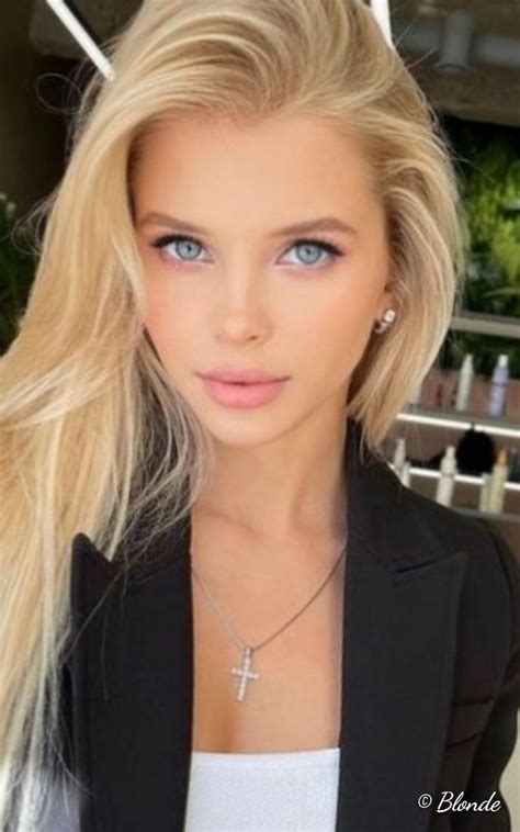 A Beautiful Blond Woman With Blue Eyes Wearing A Black Blazer And Cross Necklaces