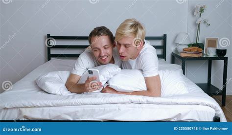 Homosexual Couple Hugging Looking At Smartphone Camera When Making