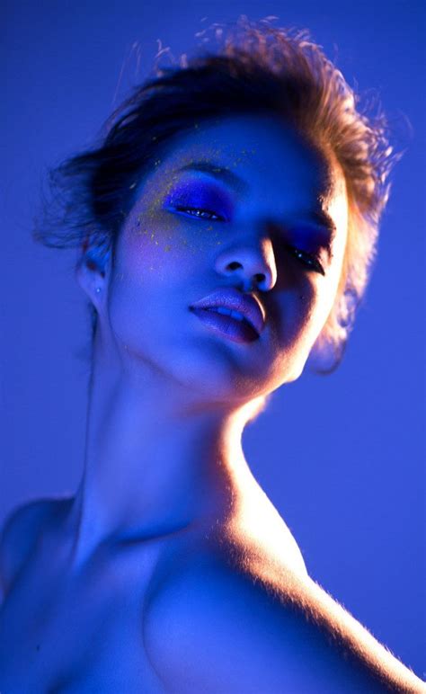 A Naked Woman With Blue Light On Her Face And Chest Posing For The Camera