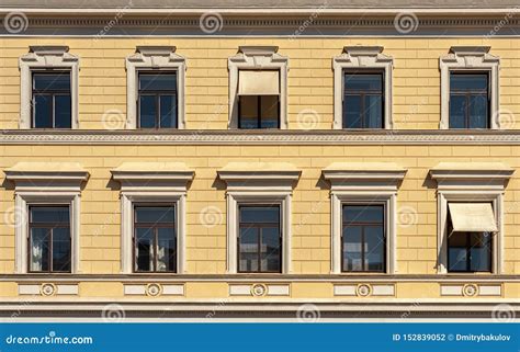 Yellow Facade Of A Beautiful City Building Windows With Cornices Stock