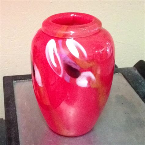 A Red Vase Sitting On Top Of A Metal Table Next To A Wall And Floor