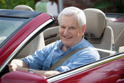 A Cheerful Senior Man Driving A Convertible Sports Car Stock Photo