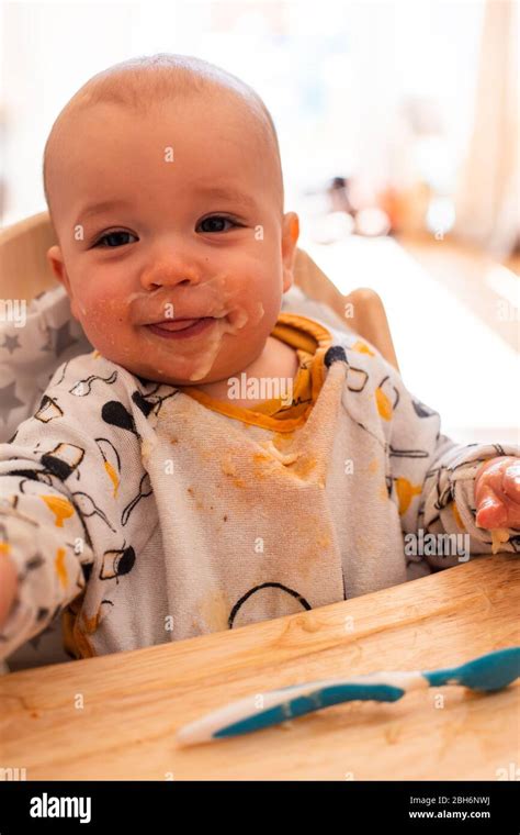 Cute Baby Eating From High Chair Stock Photo Alamy