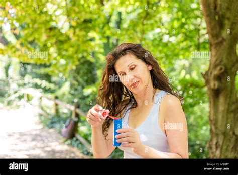 Beautiful Mature Adult Woman Dipping The Bubble Wand Into Soapy Water To Blow Soap Bubbles Stock