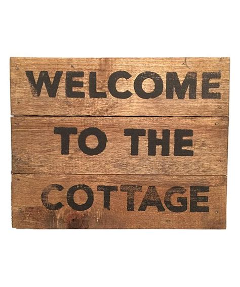 A Wooden Sign With The Words Welcome To The Cottage Written In Black