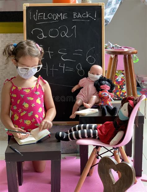 Little Girl Playing Teacher Teaching Her Dolls With A Mask Stock
