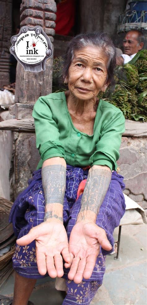 an old woman sitting on the ground with tattoos on her arms