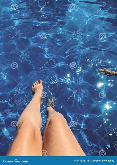 Summer Vacation And Relax Tanned Girl Legs In A Pool With Blue Water
