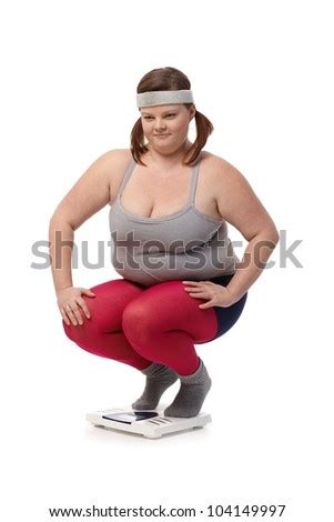 Plump Woman In Sportswear Squatting On Scale Disappointed Stock Photo