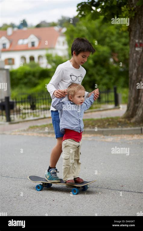 Older And Younger Brothers Riding A Skateboard Stock Photo Alamy