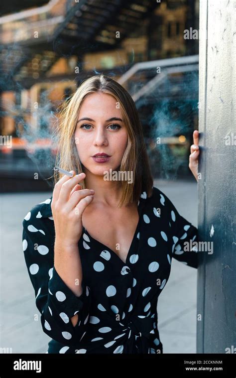 Beautiful Woman Smoking Cigarette While Standing In City Stock Photo