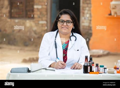 Portrait Of Young Indian Female Doctor Wear Stethoscope Write Prescription On Paper Sitting