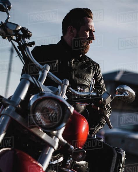 Portrait Of Biker Sitting On Motorcycle And Looking Away Stock Photo
