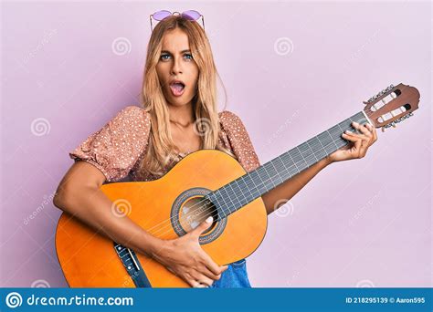 Beautiful Blonde Young Woman Playing Classical Guitar In Shock Face