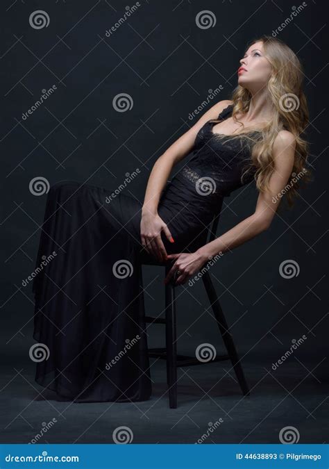 Beautiful Woman In A Black Evening Dress Posing With Chair Stock Image
