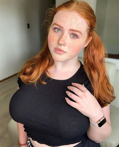 A Woman With Freckles On Her Face Is Posing For The Camera And Has Red Hair