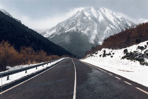 Winter Road With A Snowy Mountains In The Background By Stocksy