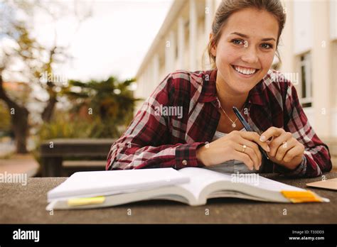 Smiling Female Student Sitting At College Campus With Books Girl