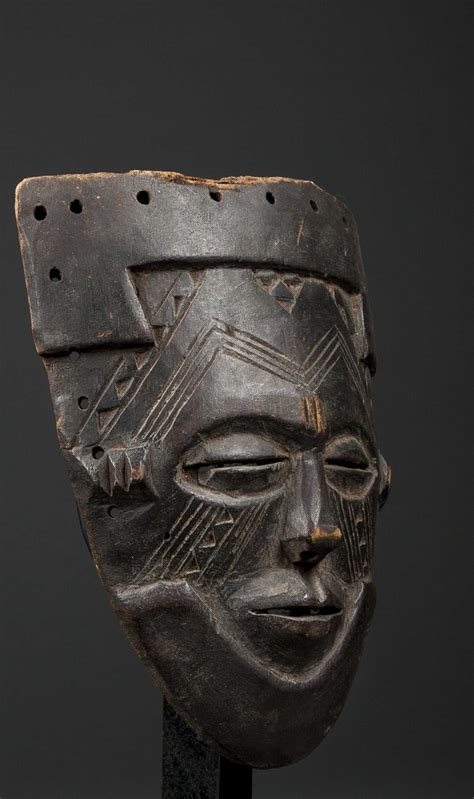 This kuba mask, known as mbwoom, is predominately made of carved wood with cowrie shell and bead embellishments. A small Kuba mask