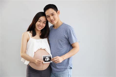 Portrait Of Asian Young Pregnant Belly Wife And Asian Husband Holding Ultrasound Film With