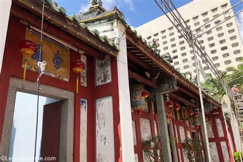The outer white walls have brick boundaries in the lowermost part where flowers and vegetation is visible. Johor Bahru Old Chinese Temple - Malaysia - Leisure and Me