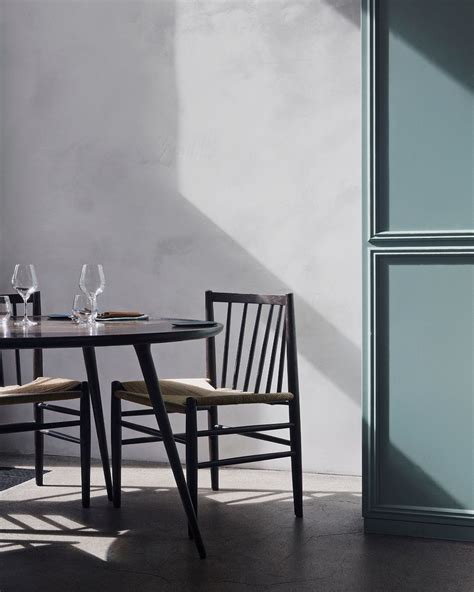 Two Chairs And A Table With Wine Glasses On It In Front Of A White Wall