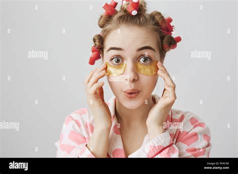Funny Playful European Girl In Hair Curlers Nightwear And Eye Patch Mask Expressing Surprise