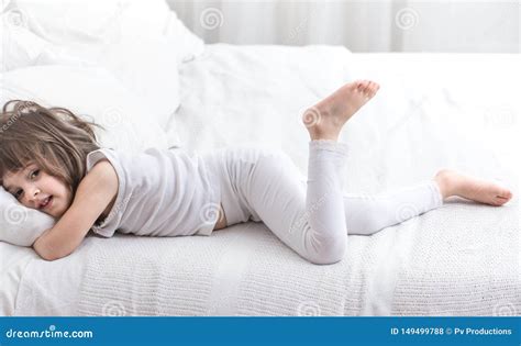 Cute Little Girl Smiling While Lying In A Cozy White Bed Stock Photo