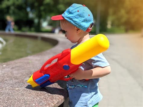 Premium Photo Happy Boy Child Playing With Water Guns Outside