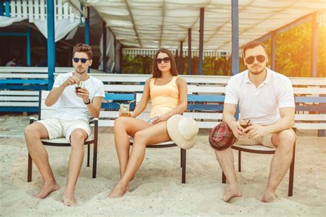 Young People Enjoying Summer Vacation Sunbathing Drinking At Beach Bar