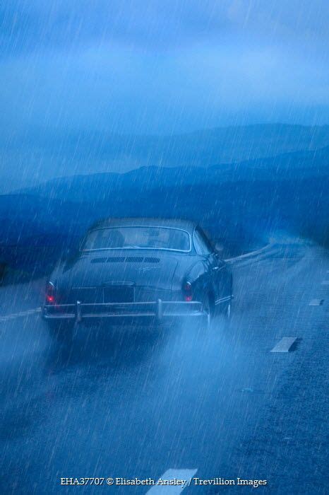 A Car Driving In The Rain On A Road