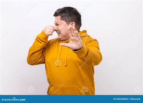 Man Grimacing In Disgust Showing Rejection With Raised Palm Pinching