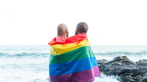 Homosexuelles Paar Das Sich Liebevoll Umarmt Eingewickelt In Die Regenbogenflagge Mit Blick