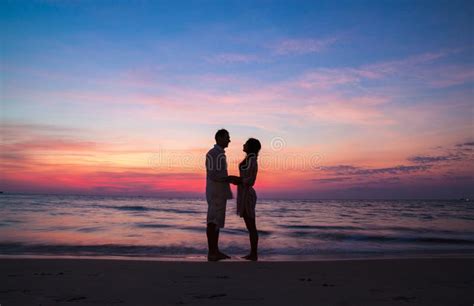 Sunset Silhouette Of Young Couple In Love Hugging At Beach Stock Photo