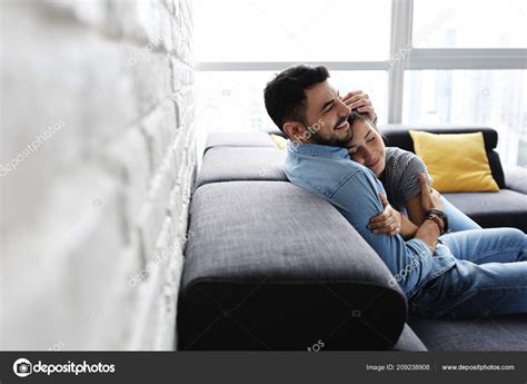 jeune couple étreignant et embrassant sur le canapé image libre de droit par diego cervo