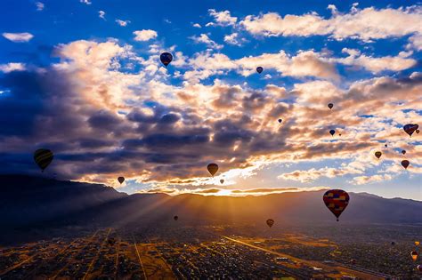 Hot Air Balloons Flying At Sunrise With The Sandia Mountains In The