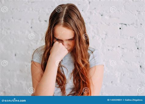 Sad Teen Girl With Long Curly Red Hair Isolated On White Brick Wall
