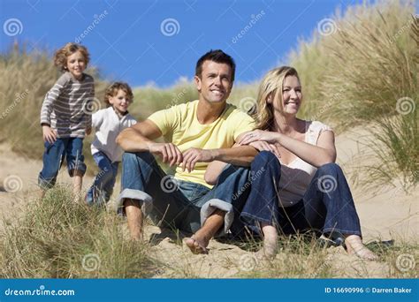 Madre Padre Y Familia De Dos Muchachos Que Se Sienta En La Playa