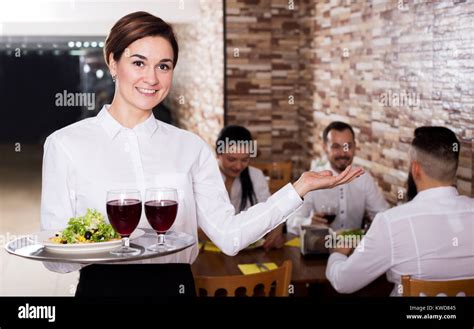 Smiling Female Waiter Welcoming Guests To Country Restaurant Stock