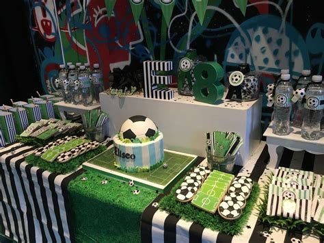 a soccer themed birthday party with green and black striped tablecloths cake water bottles and