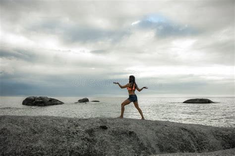 Woman Dancing Like An Egyptian On A Rock At Sunset On Bakovern Beach Cape Town Stock Photo