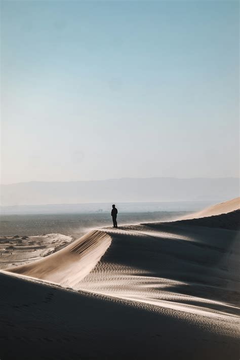 Person Standing On Desert During Daytime Photo Free Nature Image On