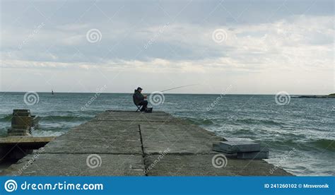 Fisherman Fishing Using Rod On Sea Bridge Construction In Spring Beach