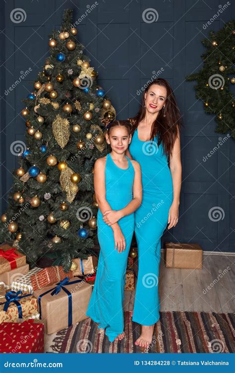 Brunettes Mom And Daughter In Identical Blue Dresses Are Standing Near