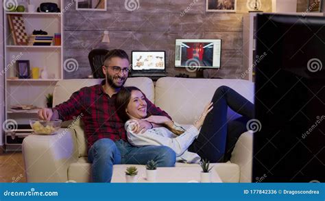 Charming Couple Lying On The Couch Watching A Movie Stock Photo Image