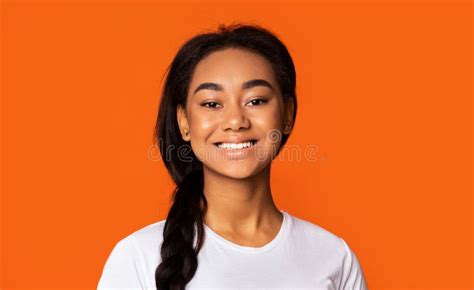 Portrait Of Smiling Teenage Girl On Orange Background Stock Photo
