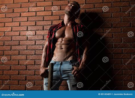 Bodybuilder Der Muskeln Auf Wand Von Ziegelsteinen Biegt Stockbild